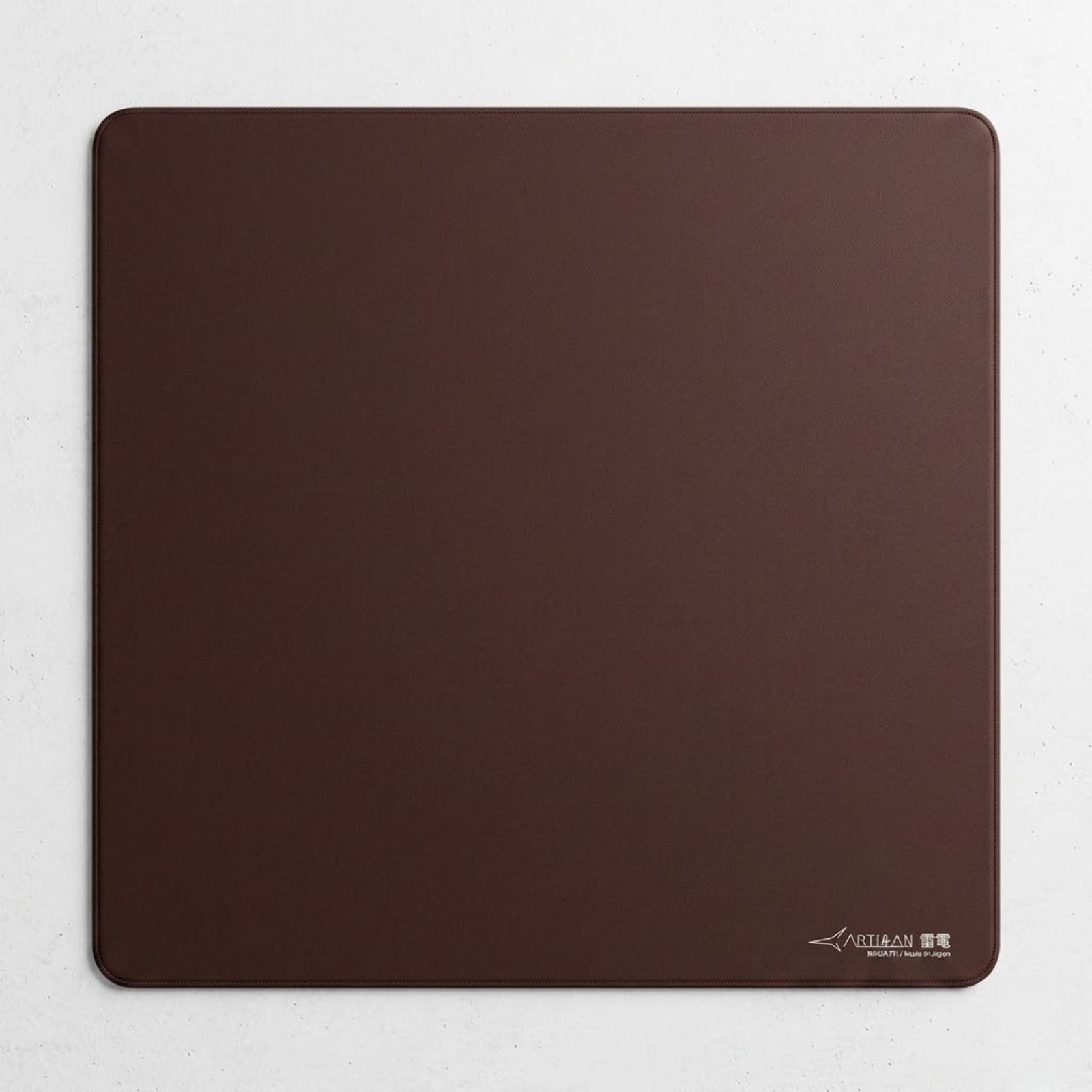 An ARTISAN Raiden MID XL Coffee Brown gaming mouse pad placed on a gaming desk with a lightweight gaming mouse positioned on the smooth cloth surface.