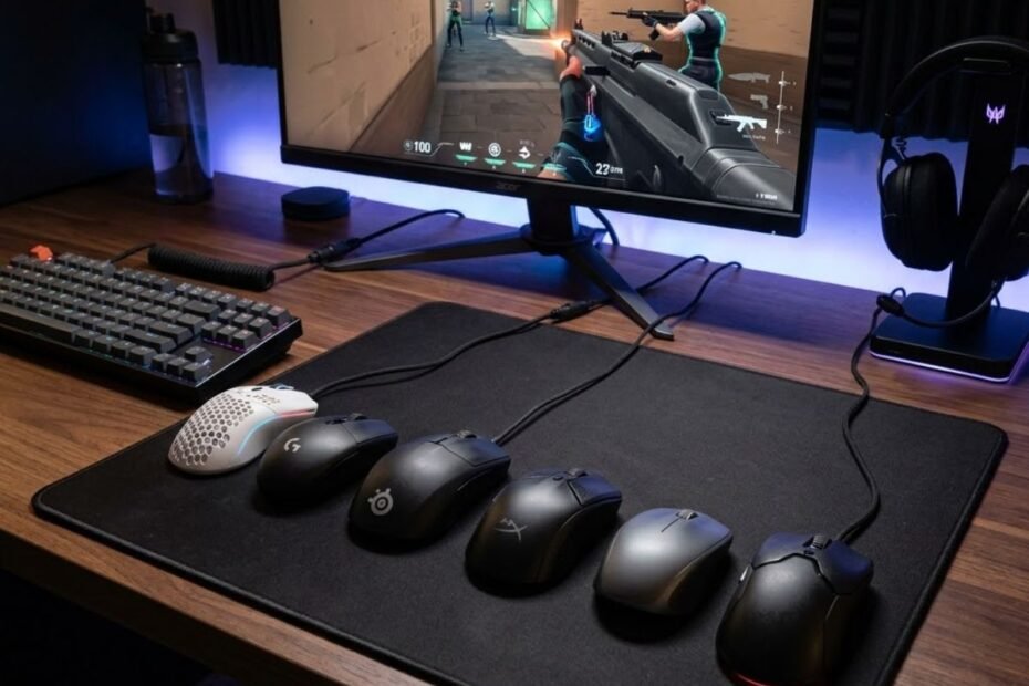 Several budget gaming mice displayed on a gaming desk with a large mouse pad and FPS game shown on a monitor.