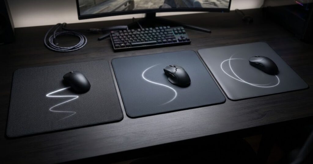 Three gaming mouse pads with different surface types placed side by side with gaming mice positioned on each surface.