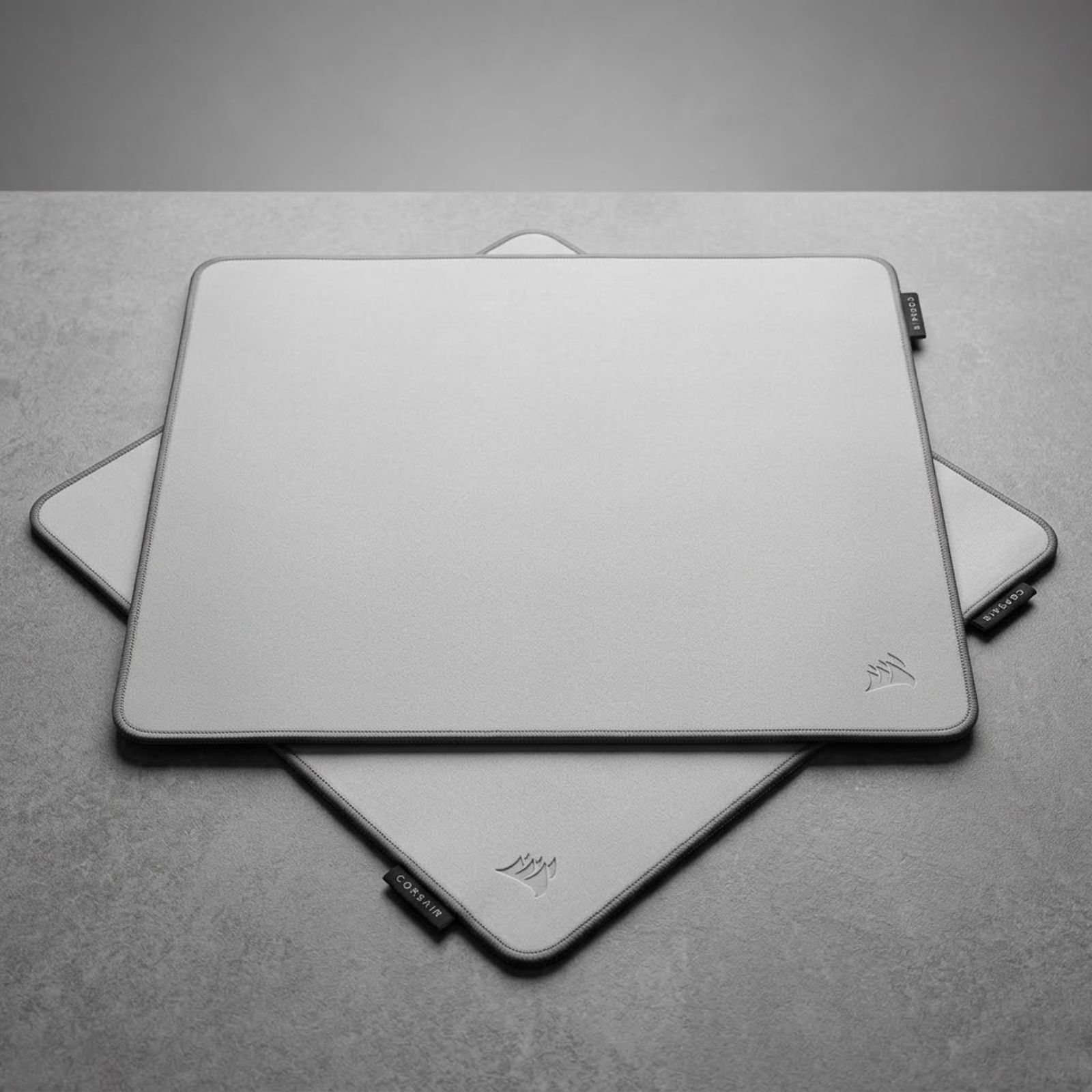 A gray Corsair MM PRO Control Cloth Large gaming mouse pad placed on a gaming desk with a lightweight gaming mouse resting on the cloth surface.