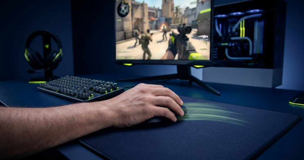 A player’s hand moving an FPS gaming mouse on a large mousepad in front of a high-refresh-rate monitor with subtle motion trails.